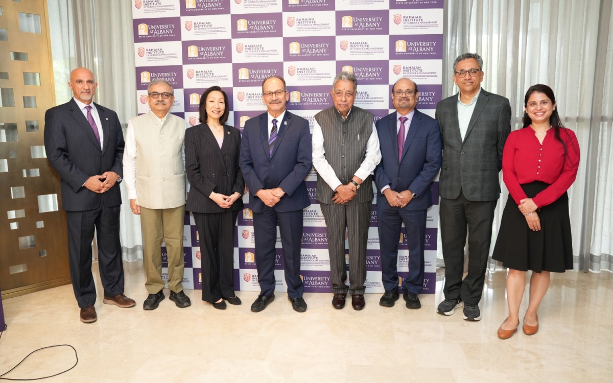 Leadership from UAlbany and RISM stand in front of a step and repeat with the logos of both universities.