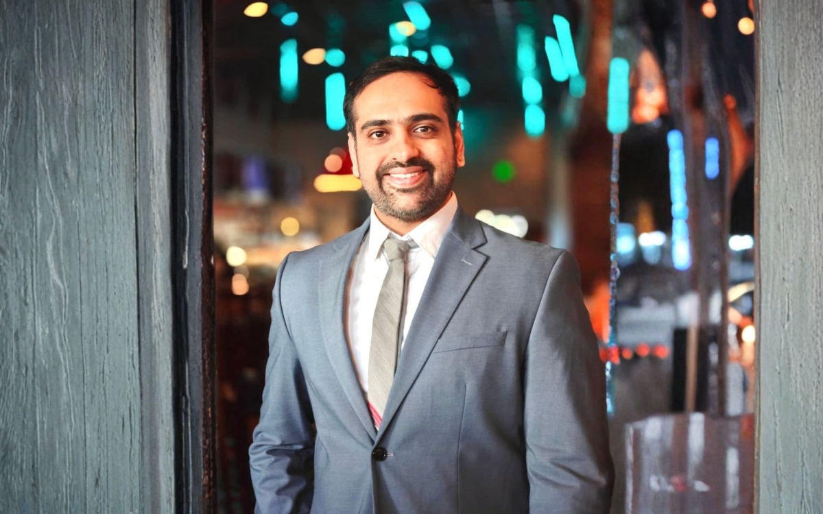 A smiling Rajas Mathkari in a gray suit with a white shirt. 