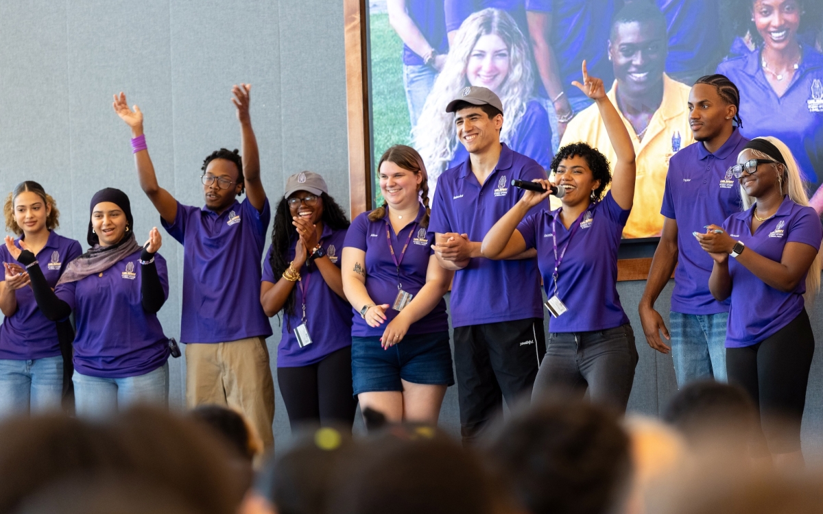 UAlbany's orientation leaders are on stage with microphones and big smiles as they introduce themselves during Connection Day