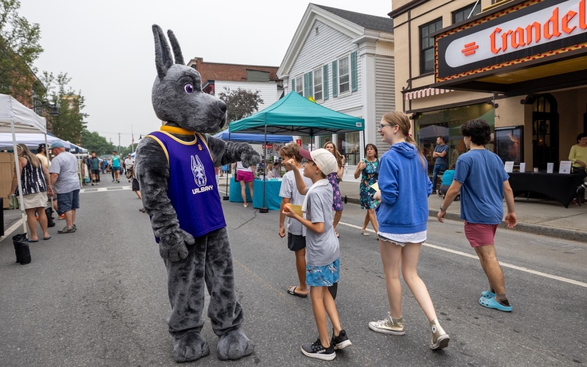 University at Albany mascot Damien gives a fist bump to a child during Chatham Summerfest on Saturday, July 18, 2026, while other attendees look on.