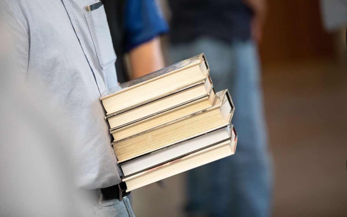 An individual carrying six books.