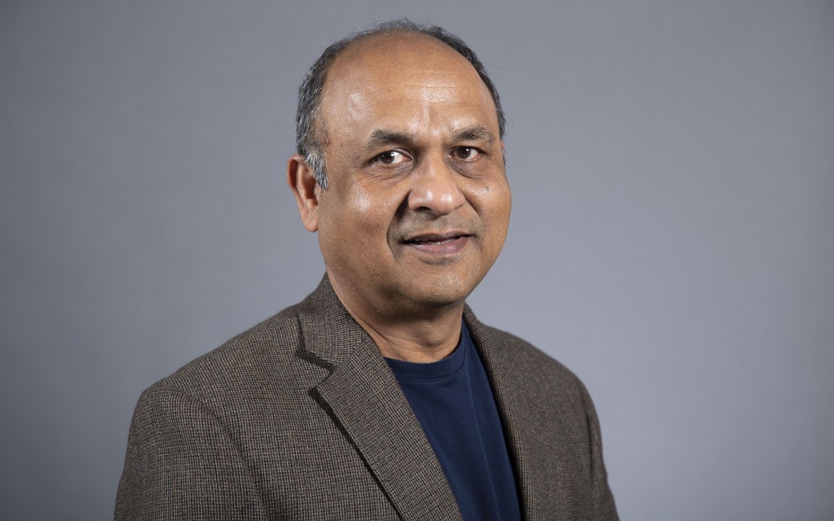 A portrait of UAlbany physicist Vivek Jain wearing a brown jacket and blue shirt.
