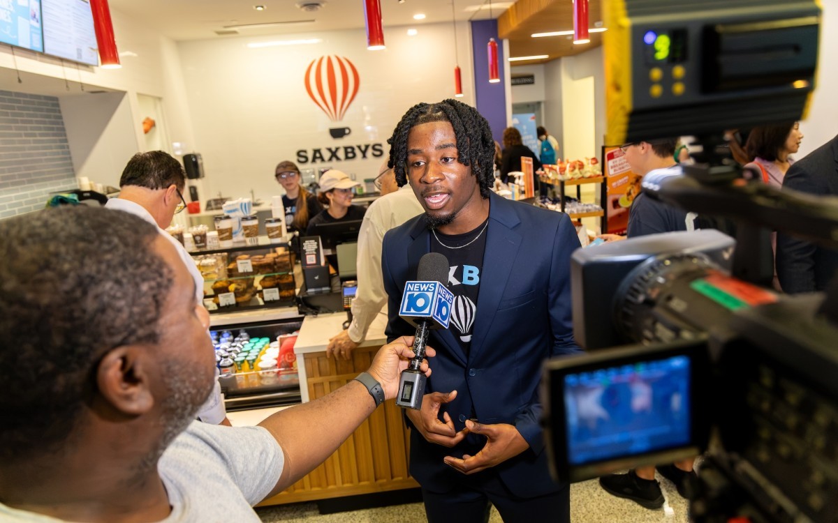 A young man speaks to a reporter who is holding a microphone that reads News 10.