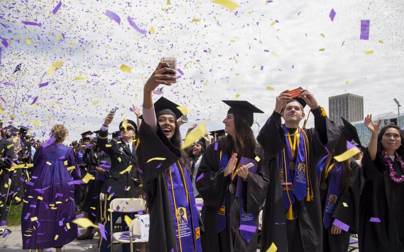 UAlbany students celebrate around purple & gold confetti.