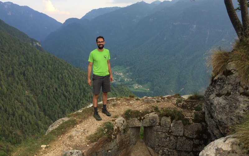 Justin Minder stands atop a rock-climbing cliff in Serrada, Italy during the International Conference on Alpine Meteorology in 2019.