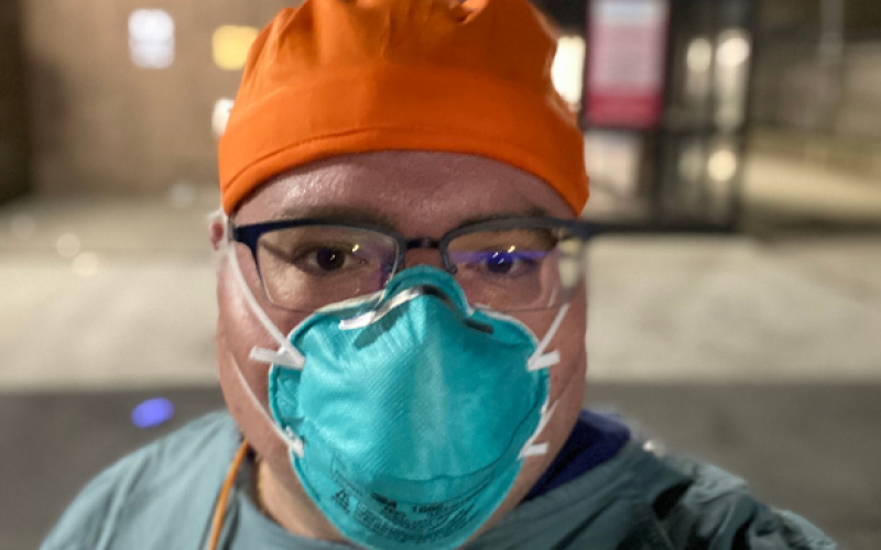 MPH student Lou Rotkowitz wears a blue face mask and an orange hat for a selfie.