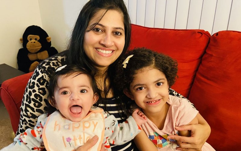 Prachi Bharadwaj smiles and holds her two young daughters on her lap