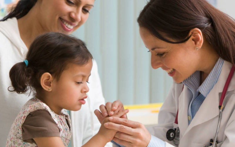 Female physician holding the hand of a small child.