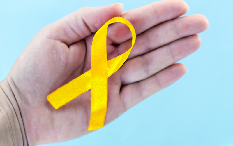 Photo of a person's palm holding a a yellow ribbon