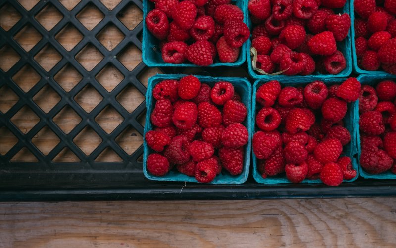 Cartons of raspberries sitting on a wooden table