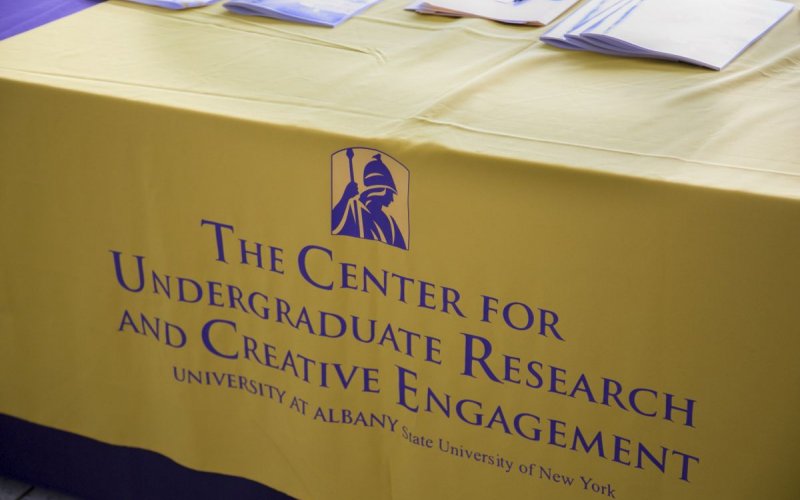 A table with a yellow tablecloth with the words " The Center for Undergraduate Research and Creative Engagement"