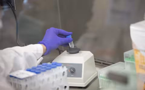 A technician at the RNA Institute analyzes a test tube with saliva in it.