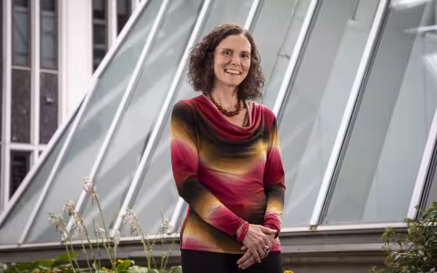 University at Albany sociologist Samatha Friedman stands by a glass stucture and smiles