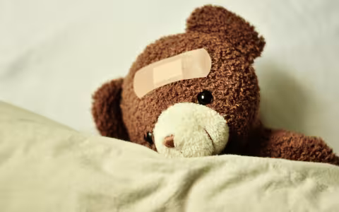 A teddy bear has a band aid on its head.