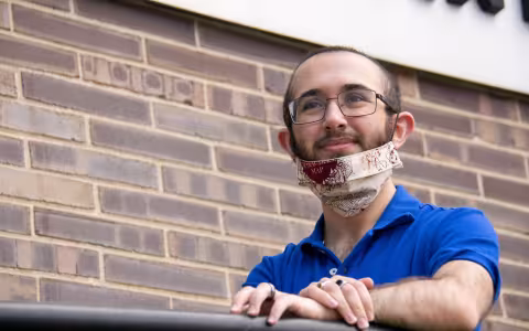 A student stands outside the Albany County Department of Health, wearing a face mask.
