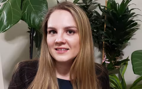 Portrait of Tatyana Tarasevich, wearing black. Plants can be seen in the background.