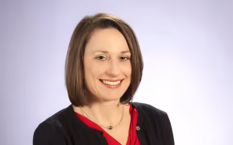 A portrait studio shot of professor Erika Martin, wearing a red shirt and black cardigan.