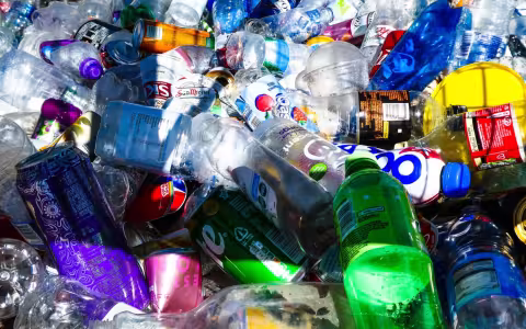dozens of single use cans and plastice bottles are piled together