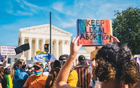 Protesters in front of the Supreme Court hold signs reading "Keep Legal Abortion" and "Our Future Our Fight Our Bodies"