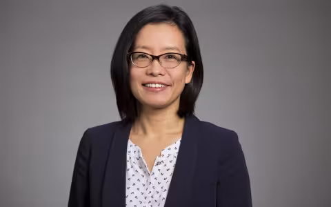 UAlbany School of Business Associate Professor Na Dai portrait - a woman wears glasses and a blue jacket.