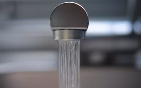 Water streams out from a silver kitchen faucet.