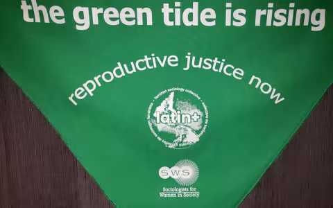 Green flag with text saying Green Tide Reproductive Justice Now on it