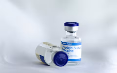 Two bottles of COVID-19 mRNA vaccines, one laying on its side.