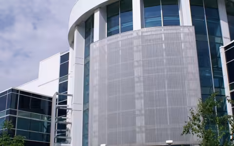 An exterior photo of a white metal and glass laboratory building that is home to the College of Nanoscale Science and Engineering.