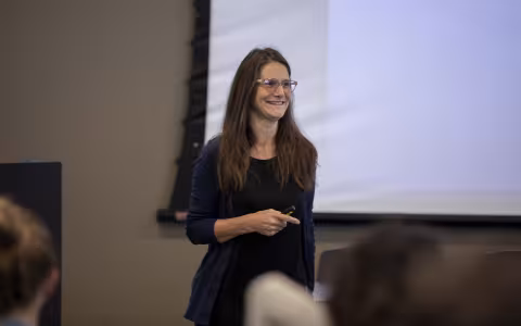 A woman speaks in front of a projector screen at the UAlbany mathematics conference.