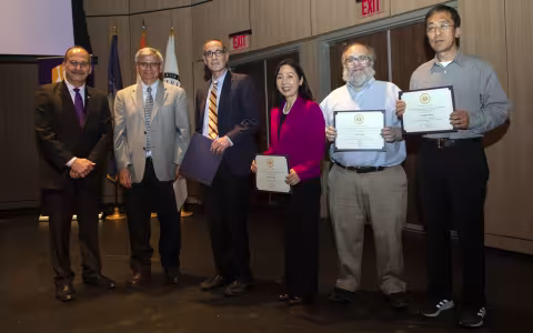 Winners of the President's Excellence Award for Research and Creative Activities pos, holding their certificates, with the President