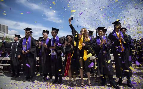 Purple and gold confetti surrounds new graduates at the UAlbany Entry Plaza lawn.