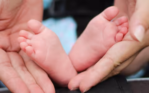 Baby feet held in two hands.