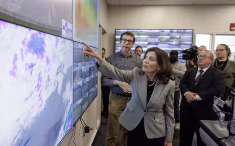 Gov. Kathy Hochul points at an air quality monitoring screen inside the NYS Mesonet operations center at ETEC.