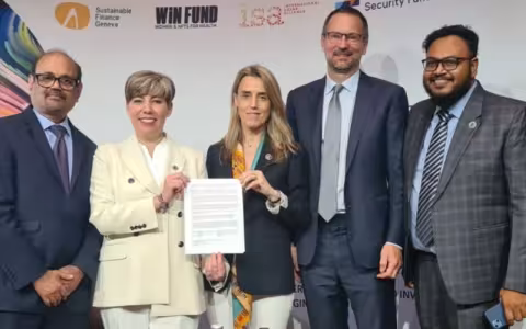 Five people standing in a line shoulder to shoulder, including two women holding a signed document.