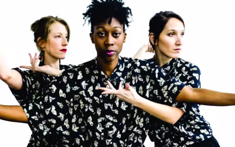 three dancers in black/white print shirts are intertwined with their arms