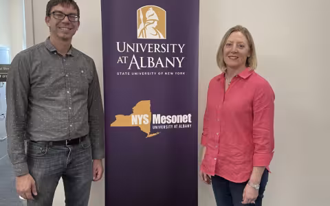 Nick Bassill and Jeannette Sutton stand in front of purple NYS Mesonet step and repeat banner.