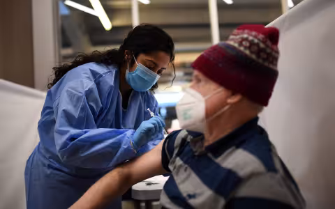 An older man is vaccinated by a nurse from the NYS National Guard at Yankee Stadium in the Bronx.