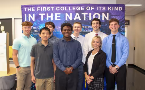 Marcie Fraser stands with EPICH students in front of a CEHC banner.