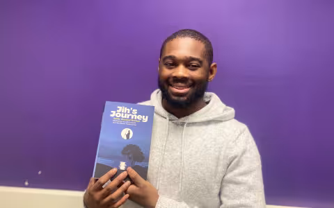 Xavier McClean posing with his novel, Jih's Journey. 