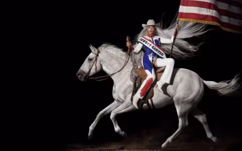 Beyonce rides side-saddle on a white horse, carrying an American flag and dressed in red, white and blue cowboy-inspired garb