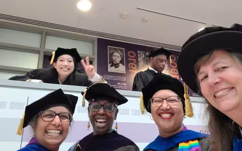 Nora Lum smiles and poses with WGSS faculty at the UAlbany commencement ceremony.