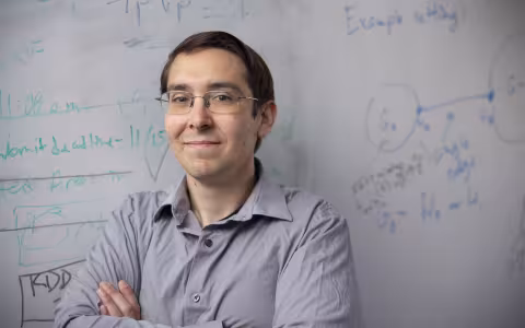UAlbany Assistant Professor Abram Magner stands in front of his white board with equations in the background. (Photo by Brian Busher)