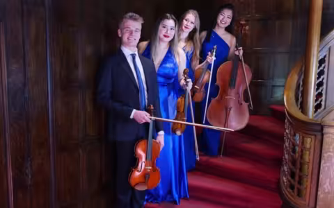 Four musicians stand on a staircase with their instruments