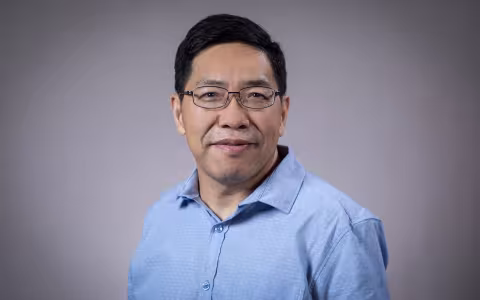 Headshot of Aiguo Dai wearing a blue button-down shirt.