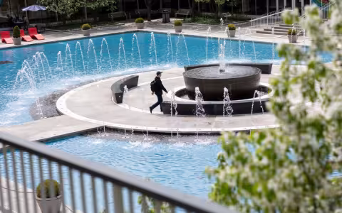 Student walking past uptown campus fountain