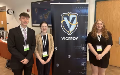 UAlbany students stand in front of VICEROY step and repeat banner.