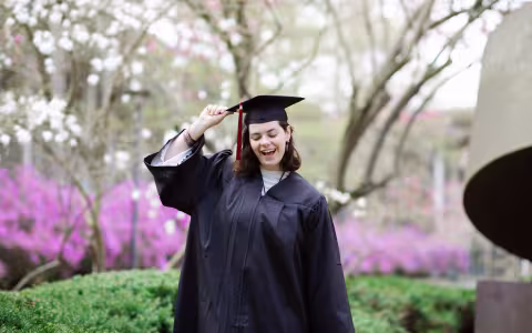 A UAlbany student poses for a photo wearing a Commencement cap and gown.