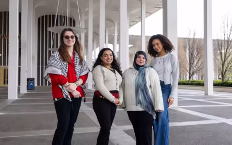 Four smiling students stand together on the Academic Podium