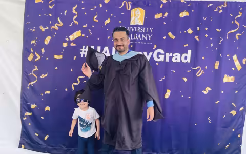 Enayat Nasir poses with his young son for a photo at UAlbany's Spring 2023 Commencement.
