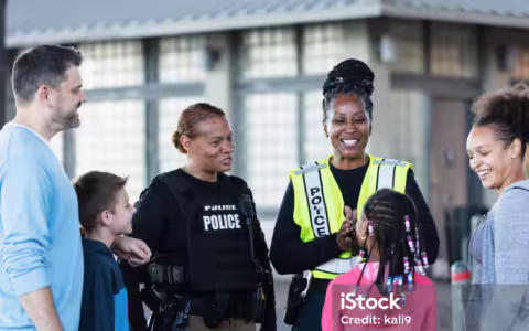 Two smiling police officers talk with parents and children.